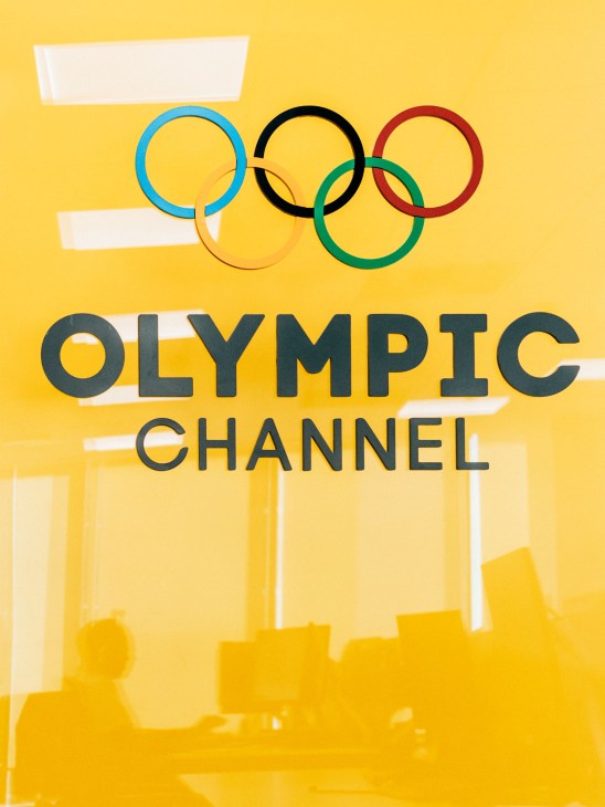 Olympic Channel logo with five interlocking rings and text on yellow background.
