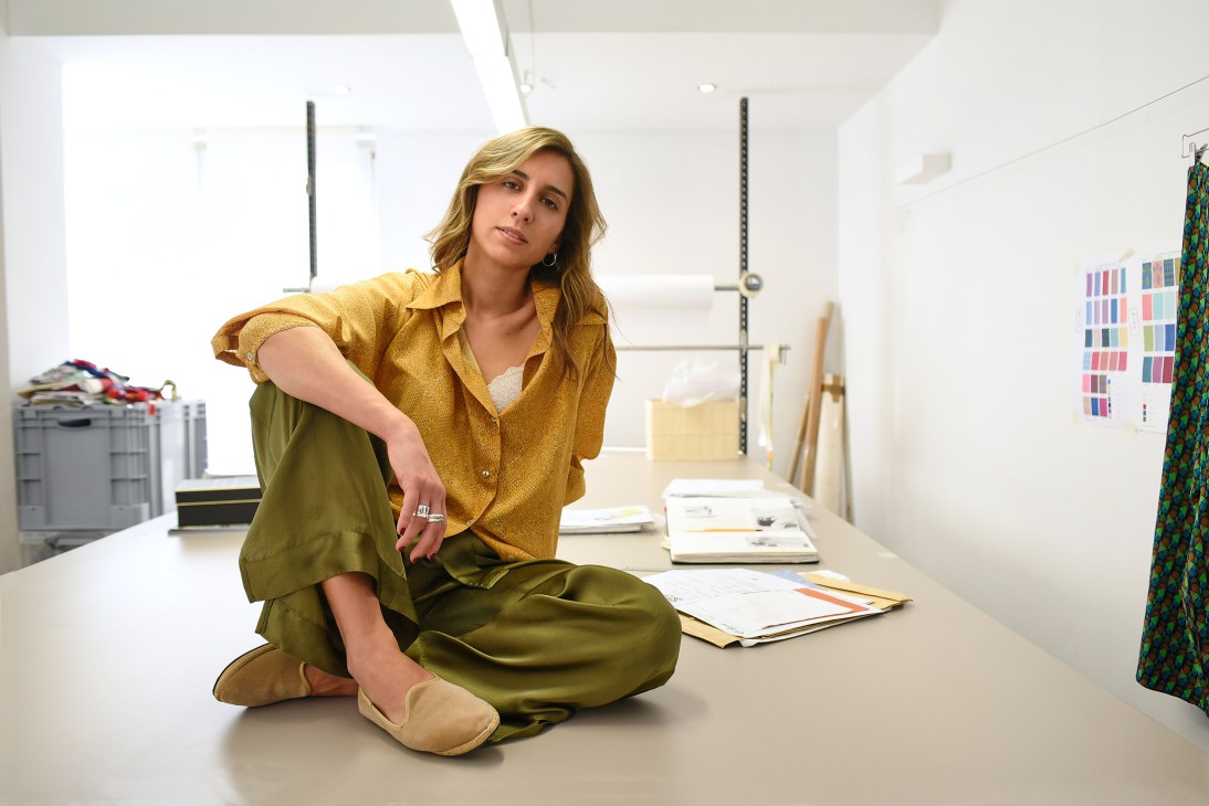 Christina Pistofidou sits in her Athens studio surrounded by fabric samples and design materials.