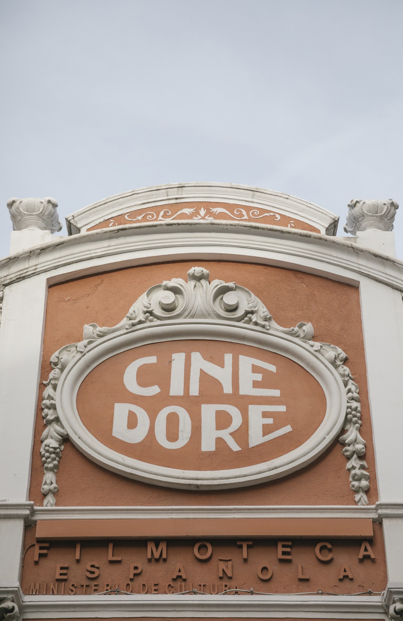 Ornate tangerine and cream facade of Cine Doré cinema with decorative classical architectural details.