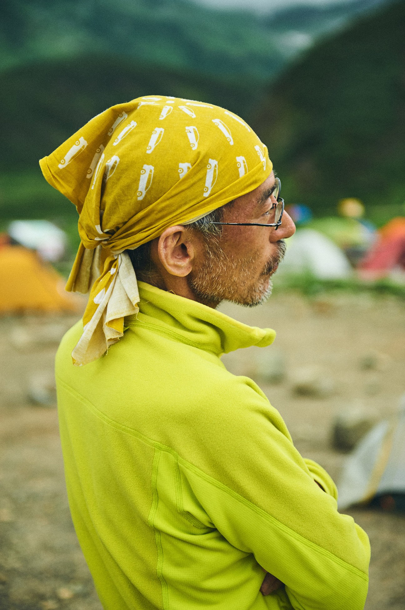 Man wearing bright yellow bandana and lime-green jacket on mountainside