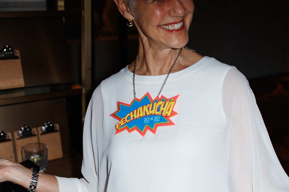 Woman wearing white t-shirt with PechaKucha 20x20 logo graphic at a Tokyo event venue.
