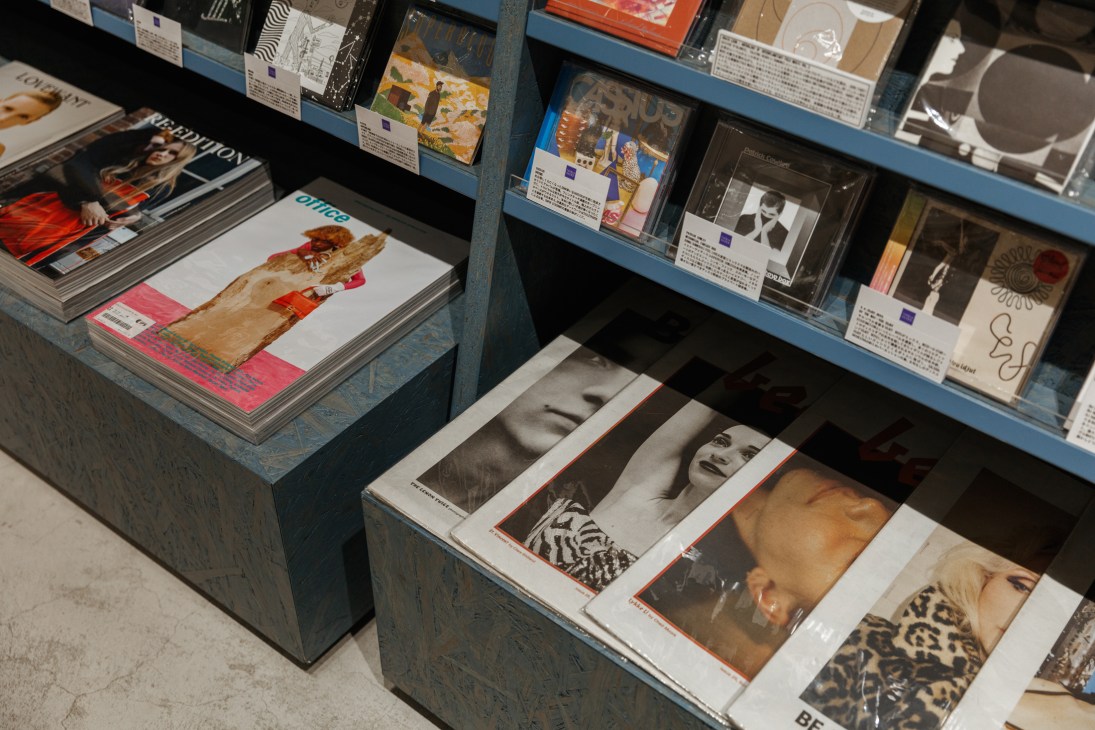 Books, magazines and vinyl records displayed on blue shelves in a Japanese station bookstore