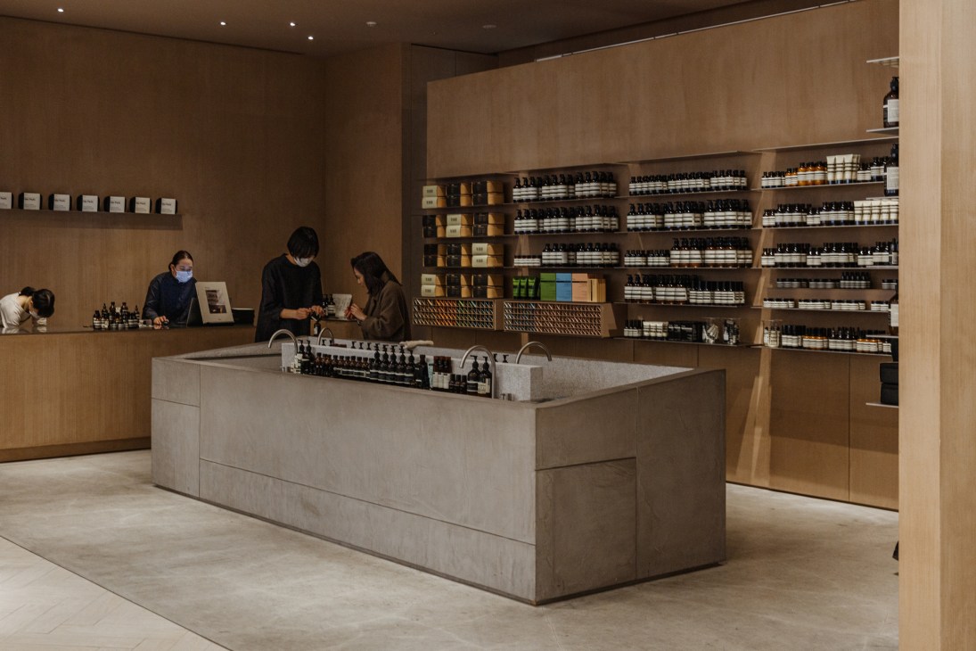 Modern retail store interior with wooden shelving displaying skincare products and customers browsing