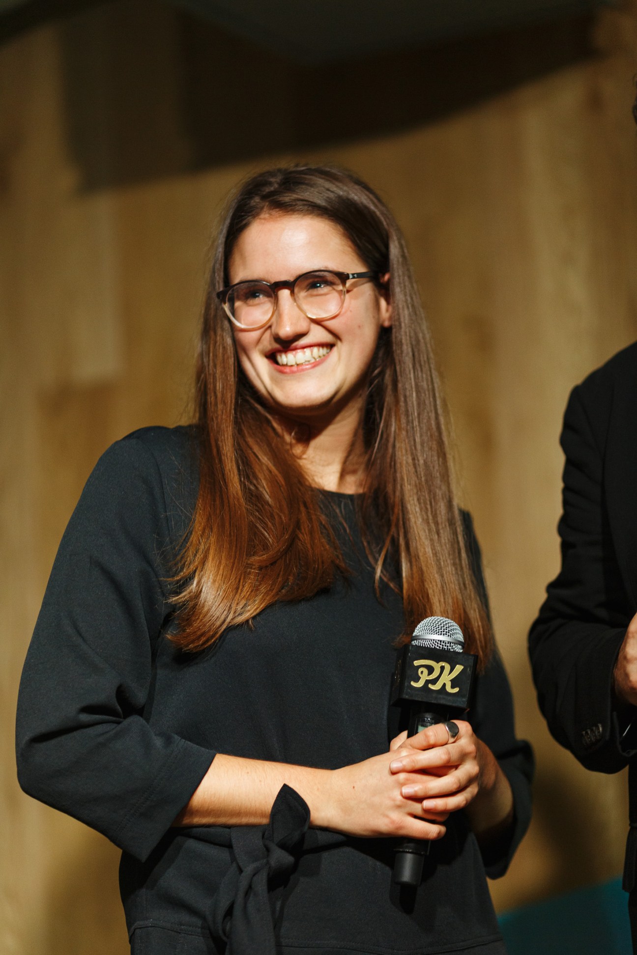 Chiara Rimella, Monocle's culture editor, smiling while holding a microphone on stage at a PechaKucha event.