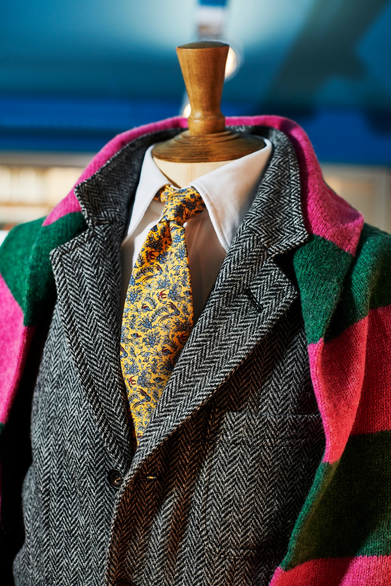 Menswear mannequin dressed in Drake's herringbone blazer with colorful striped scarf and patterned tie