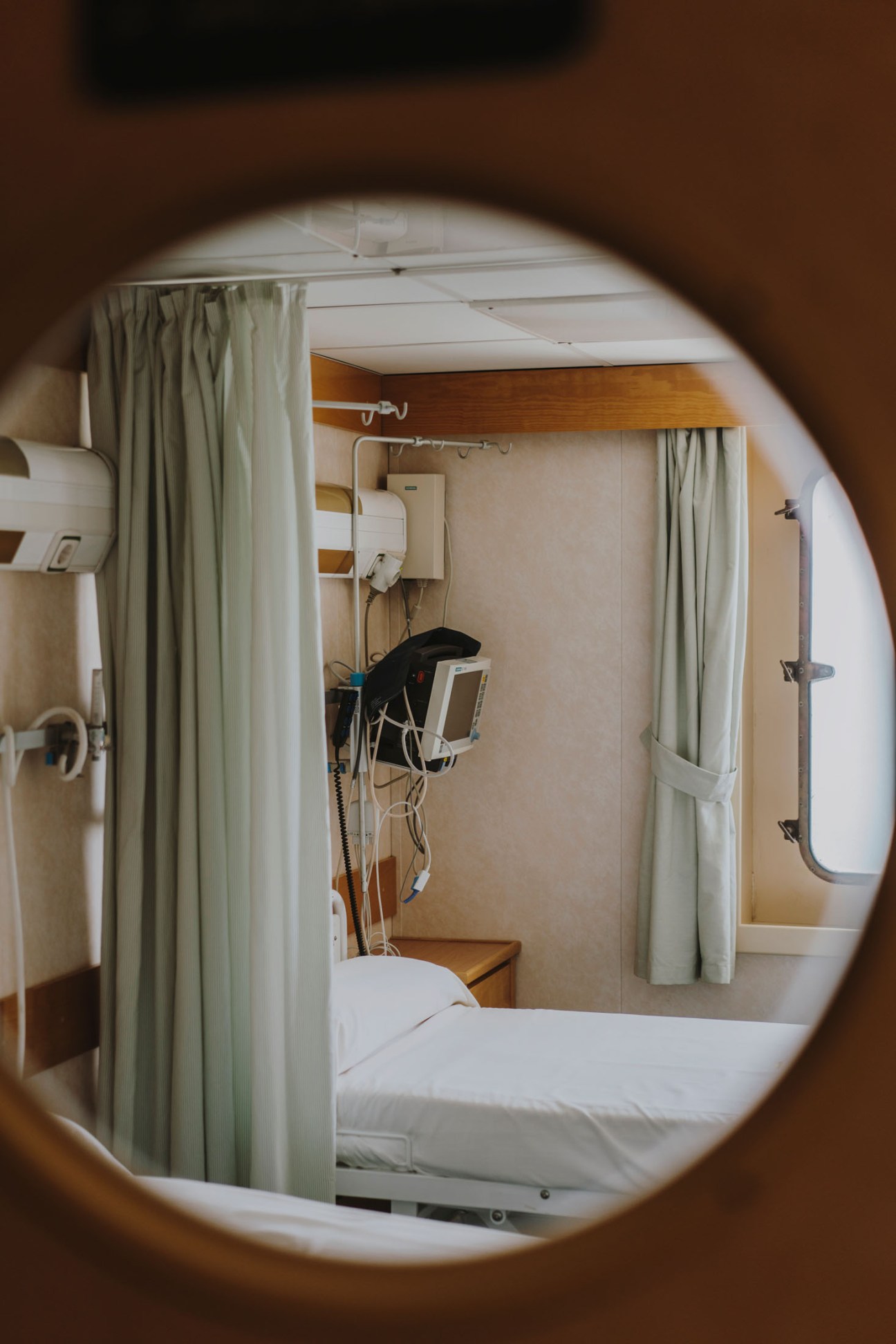 Hospital ward on the Esperanza del Mar with white bedding, medical equipment, and curtained privacy partitions.