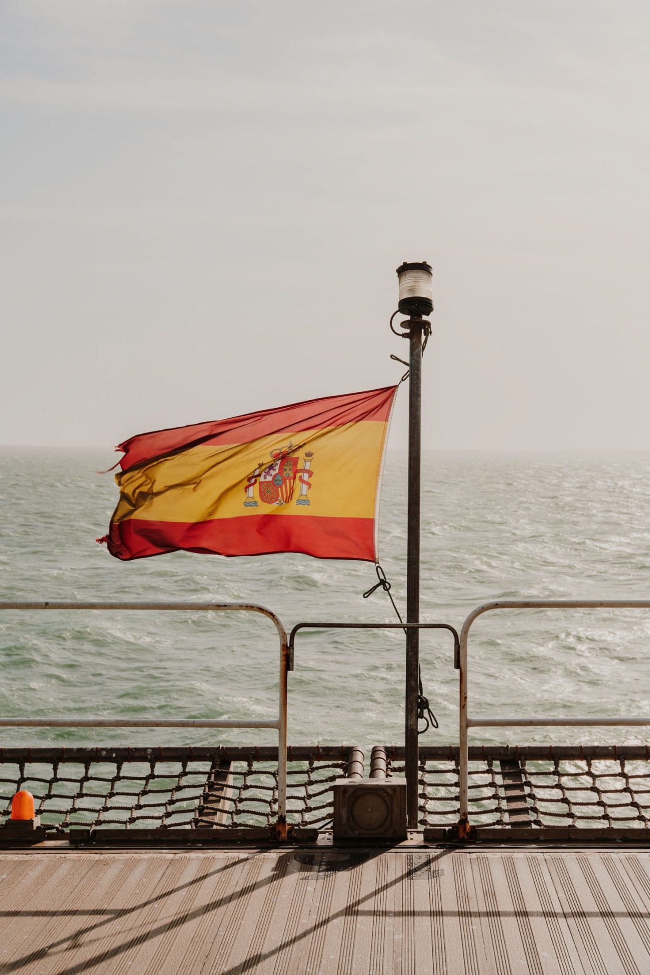 Spanish flag waving on the deck of the Esperanza del Mar hospital ship overlooking calm ocean waters.