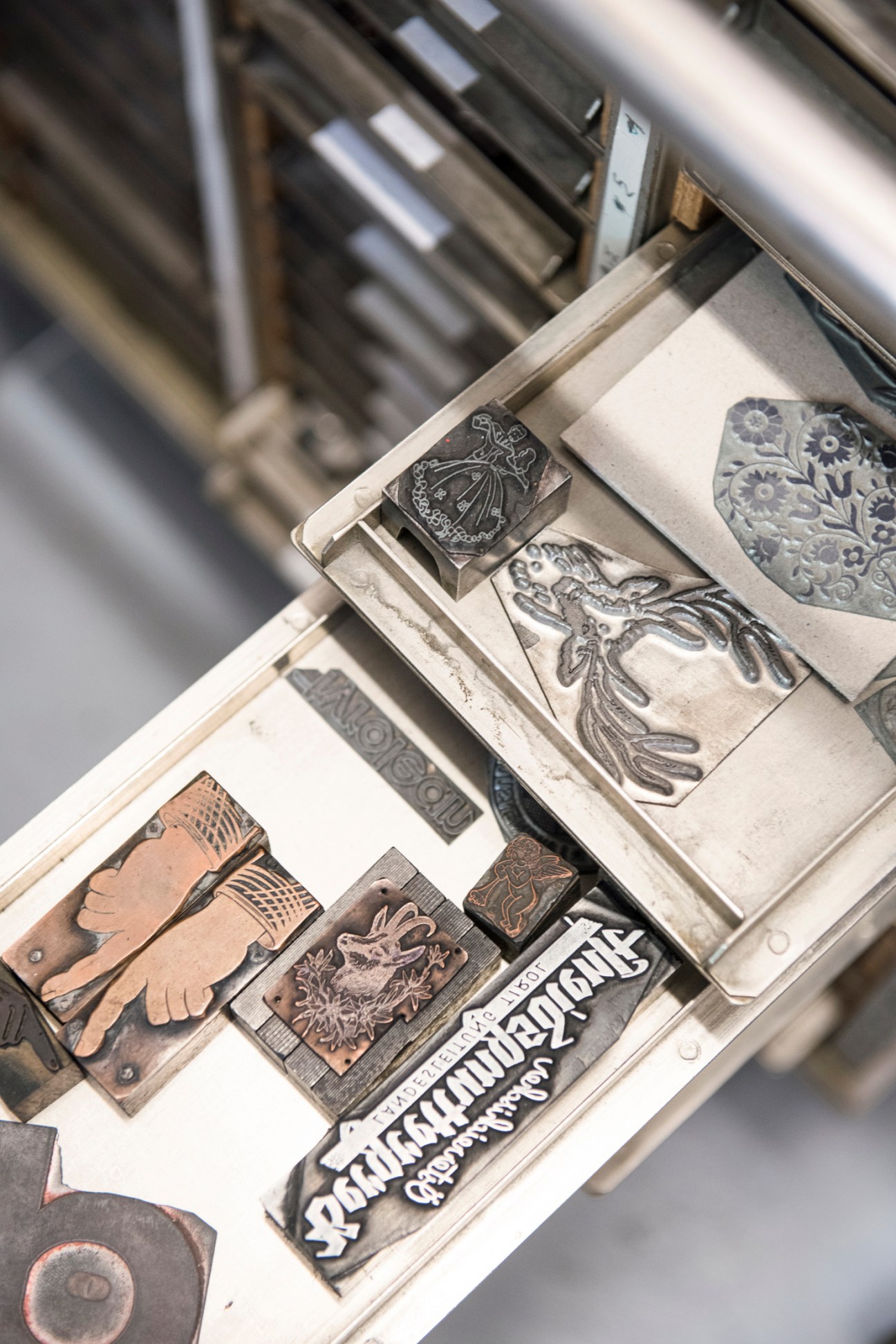 Collection of vintage metal printing blocks and type elements organized in wooden compartments