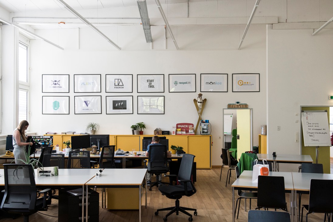 Modern office space with desks, computers, and framed startup logos on white walls at Inncubator