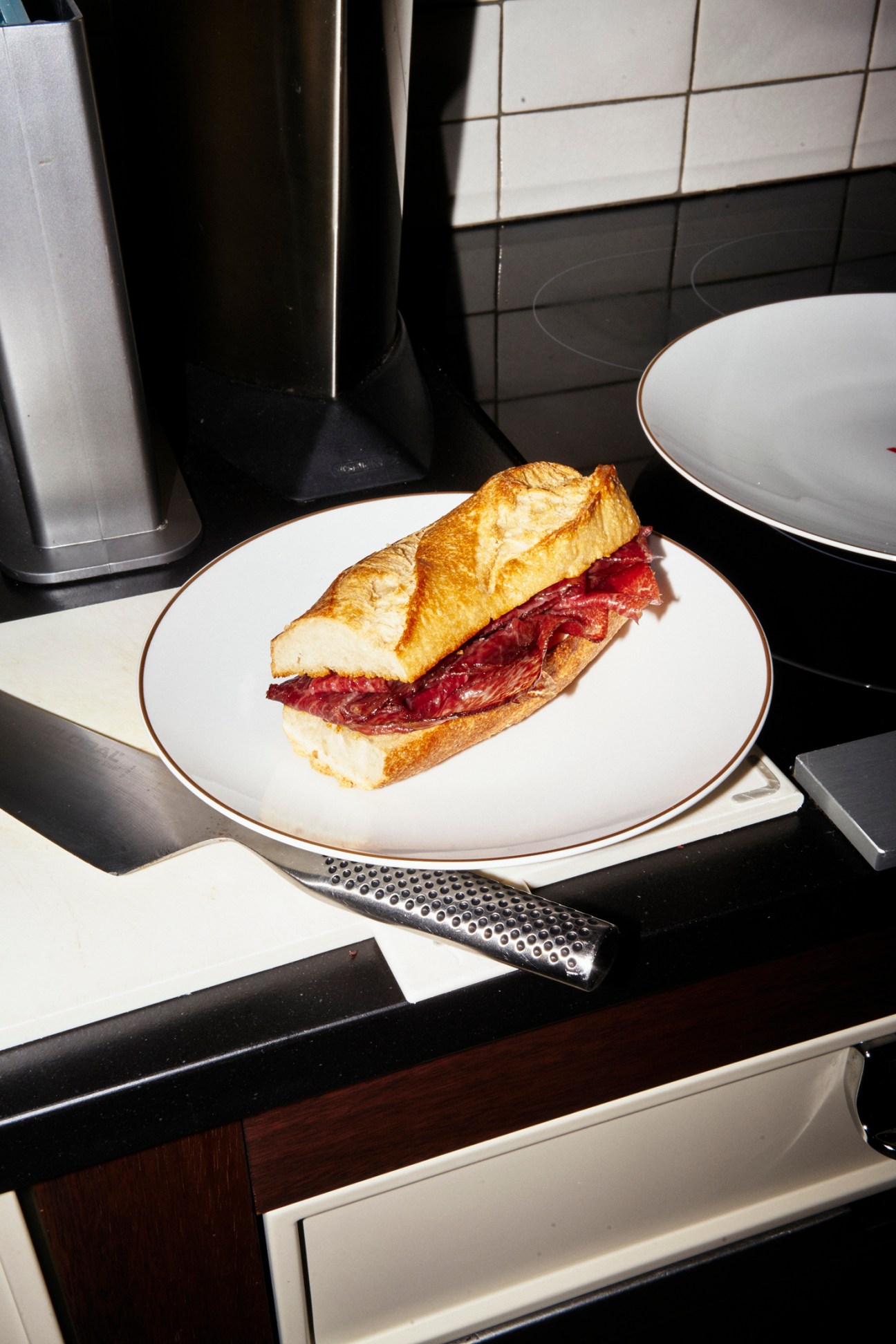 Lunch is served - a sandwich with cured meat on a white plate in a modern kitchen