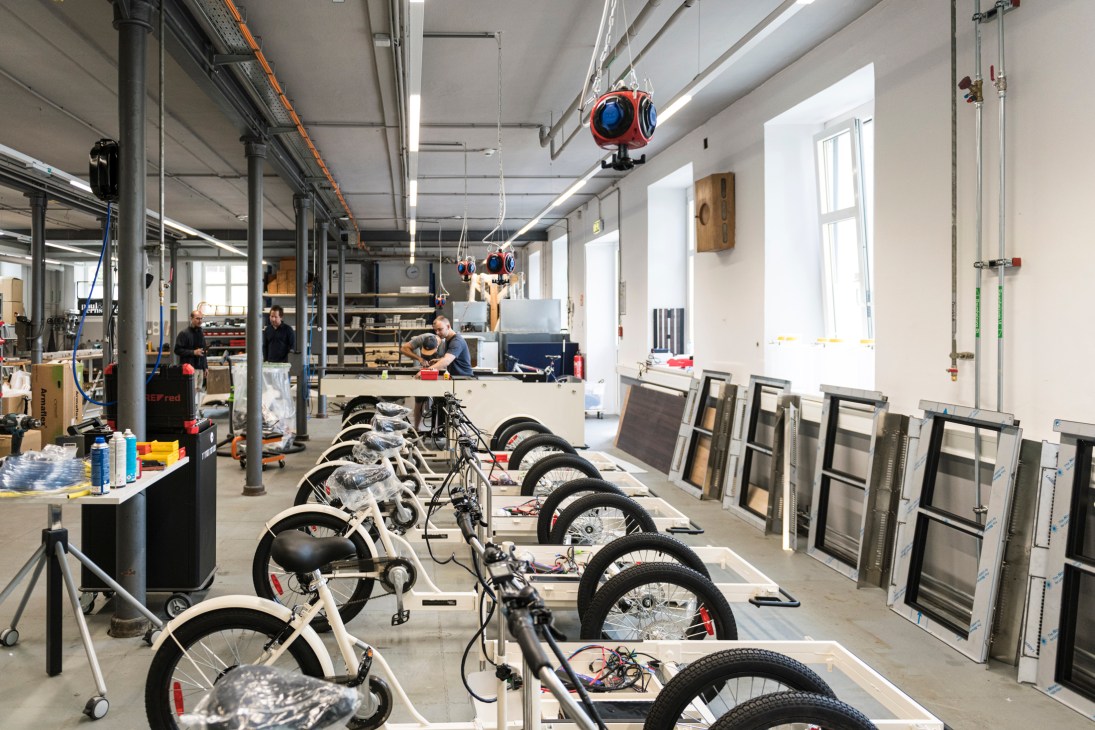 Assembly line of white electric bicycles in a modern industrial workshop with workers in background
