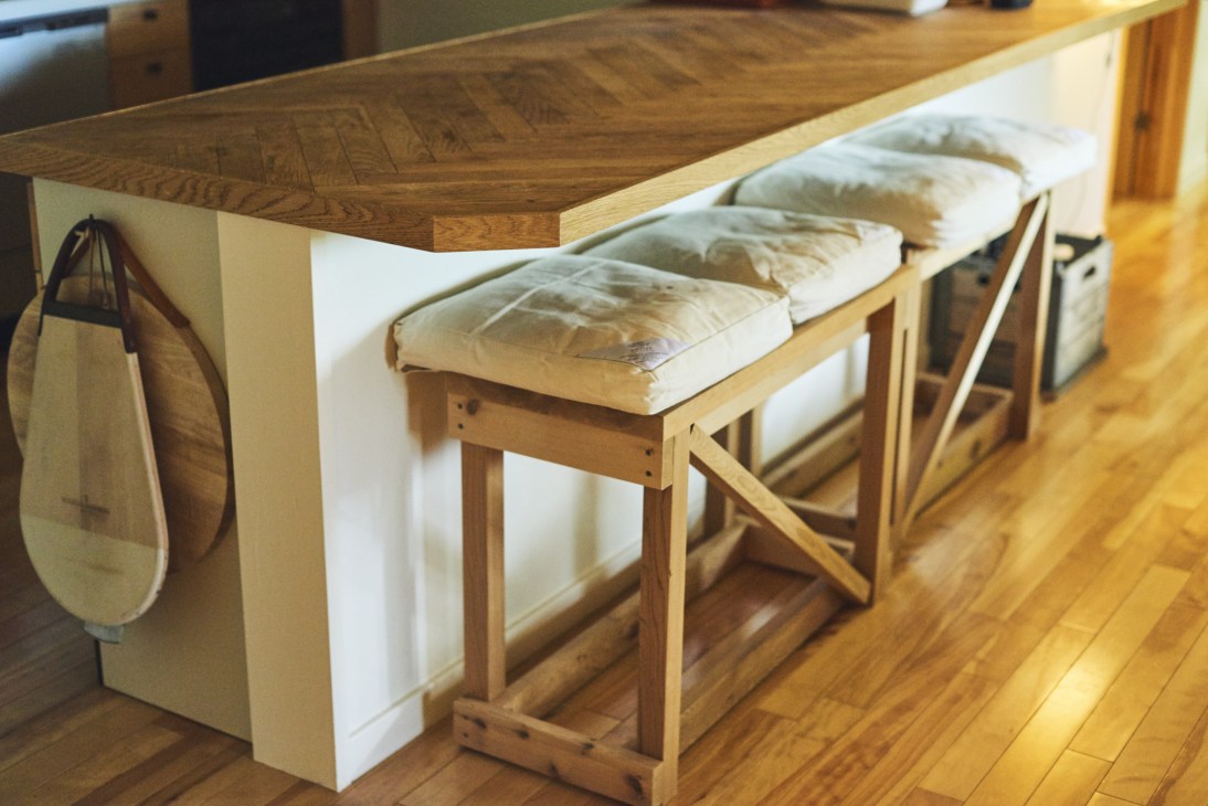 Wooden counter with benches by Takanori Ota of OFC in the kitchen