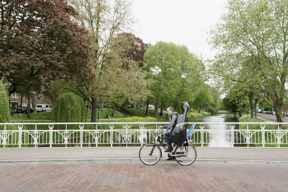 Cyclist riding along a canal path lined with trees in Utrecht, Netherlands.