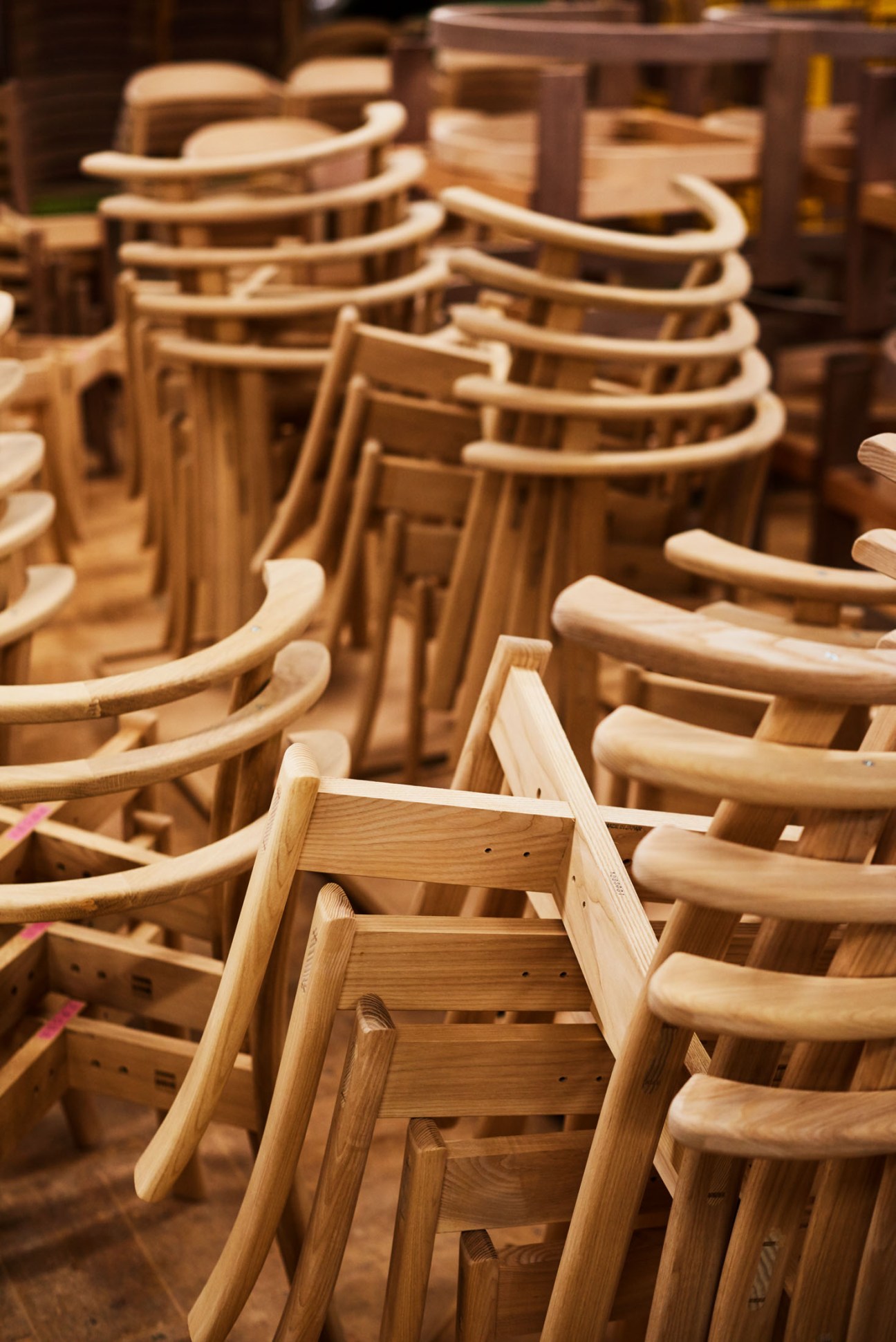 Multiple wooden chairs with curved backs in various stages of production at Conde House workshop in Asahikawa.