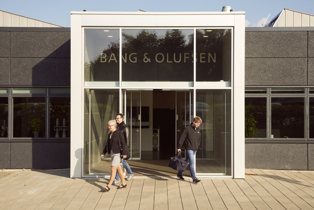 Employees walking past the Bang & Olufsen branded entrance to the Innovation Lab building.