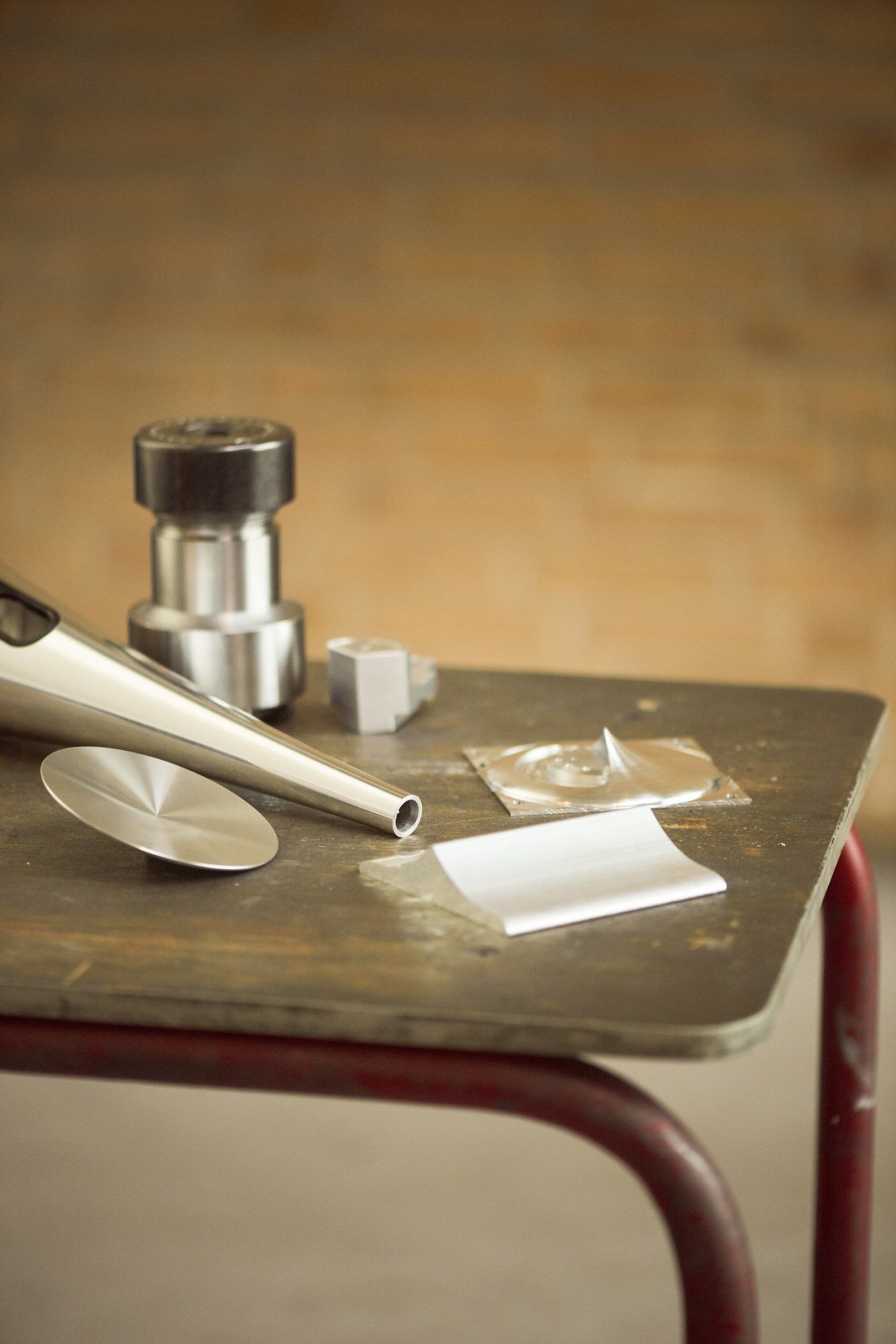 A collection of drug paraphernalia including a spoon, syringe, lighter, and packets arranged on a dark surface with a metal container.