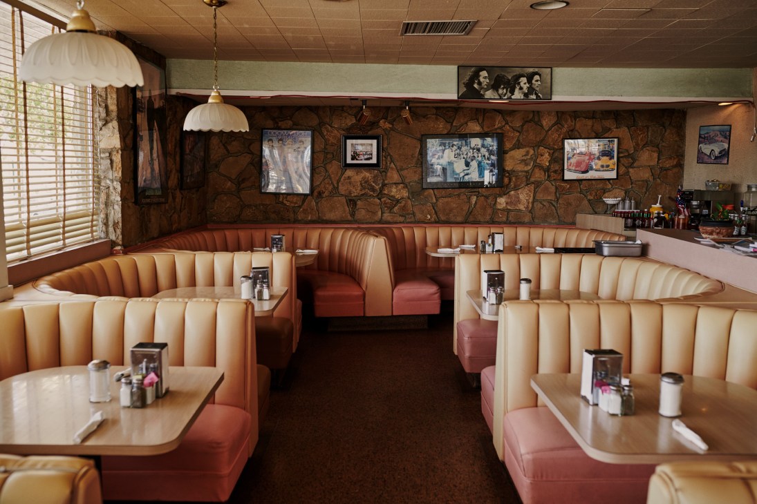Interior of Chips diner showing upholstered banquettes, pendant lights, stone walls and vintage photographs.