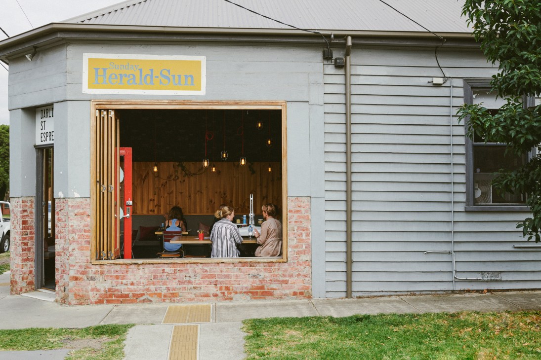 Darling St Espresso milk bar storefront with yellow signage, brick and weatherboard exterior, and customers visible inside at counter.