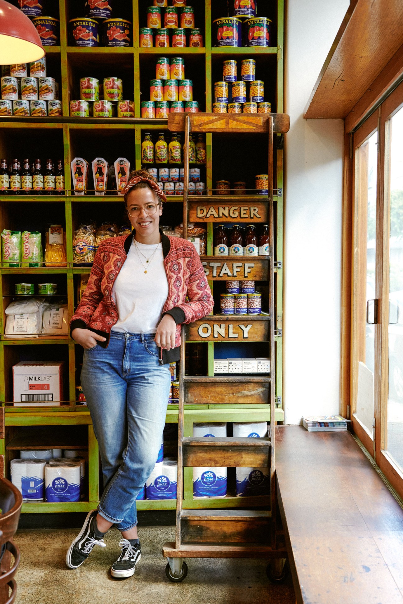 Manager Chenchen Liang stands in front of Cowderoy's Dairy shelves stocked with colorful jars and products.