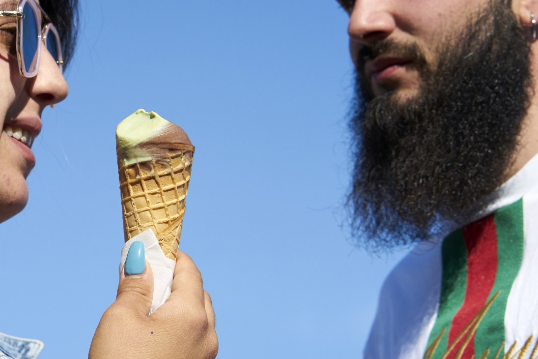 Two people with ice cream cones against a clear blue sky; existing caption identifies as Naples scene.