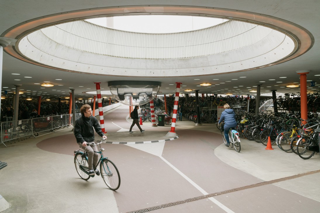 Cyclists navigate a modern underground bike parking facility beneath Groningen train station.