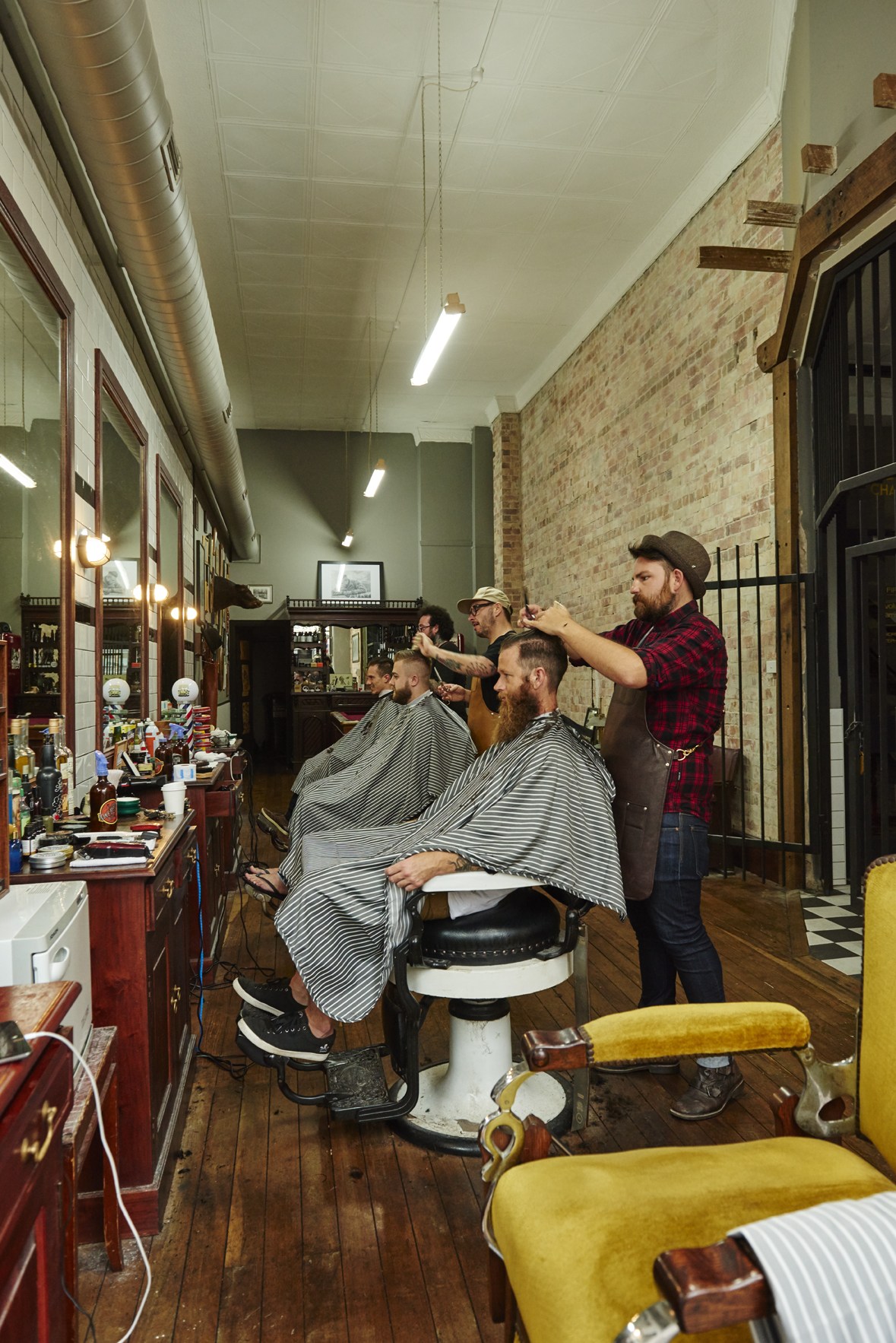 Barber cutting customer's hair at The Alibi Room barbershop in Newcastle.
