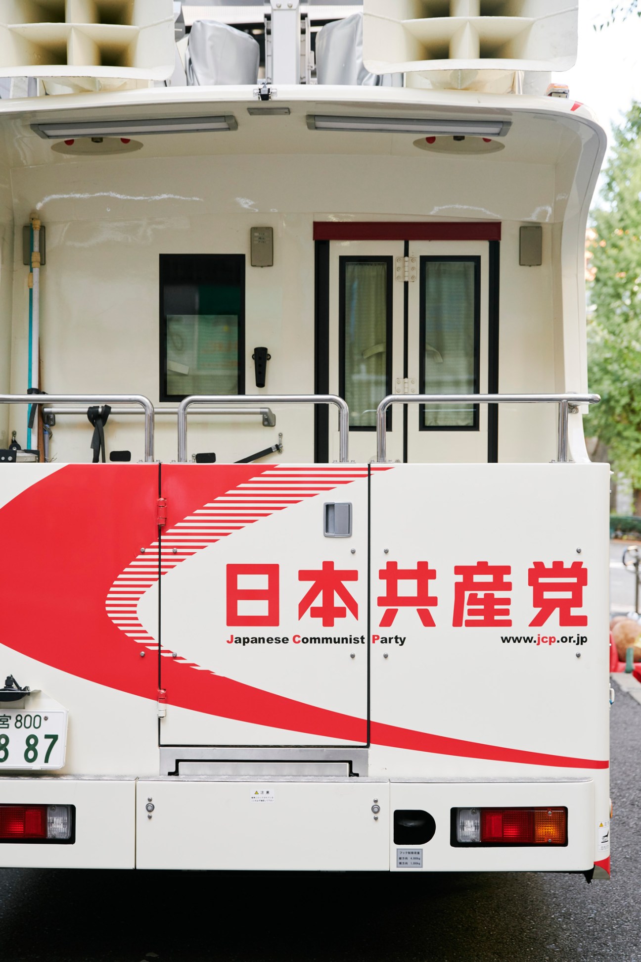 White campaign vehicle with red Japanese Communist Party logo and text on the side, parked outdoors