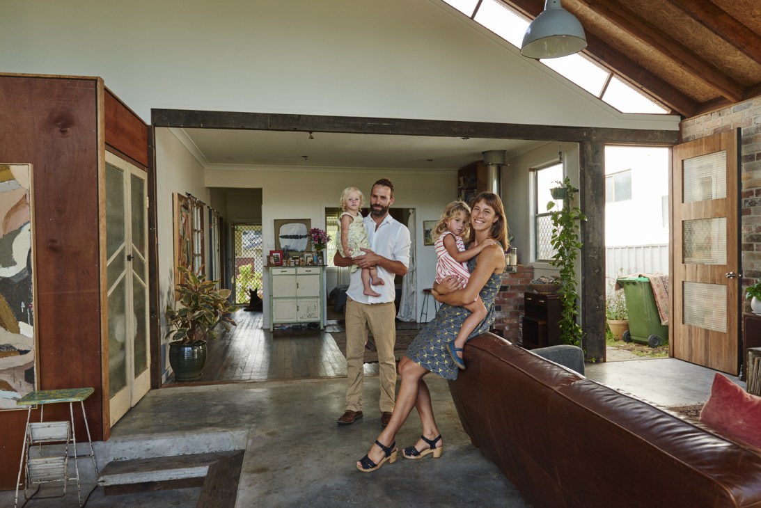 Steph Whitehead and Christopher Johnston stand with their two young children in their open-plan living room.