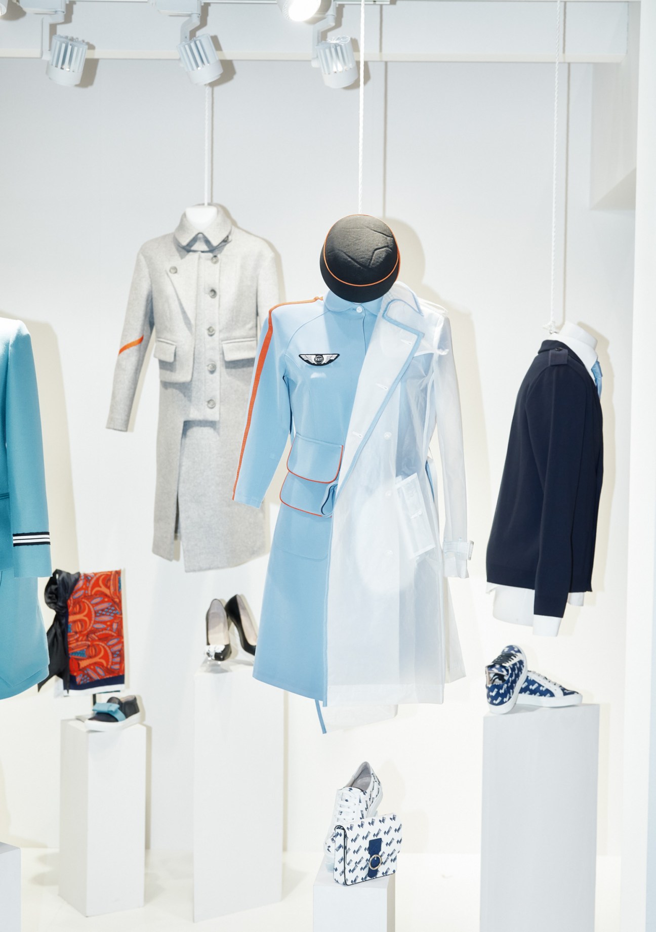 Display of innovative airline crew uniforms in various colors including light grey, sky blue, and navy, featuring modern designs with orange trim details.