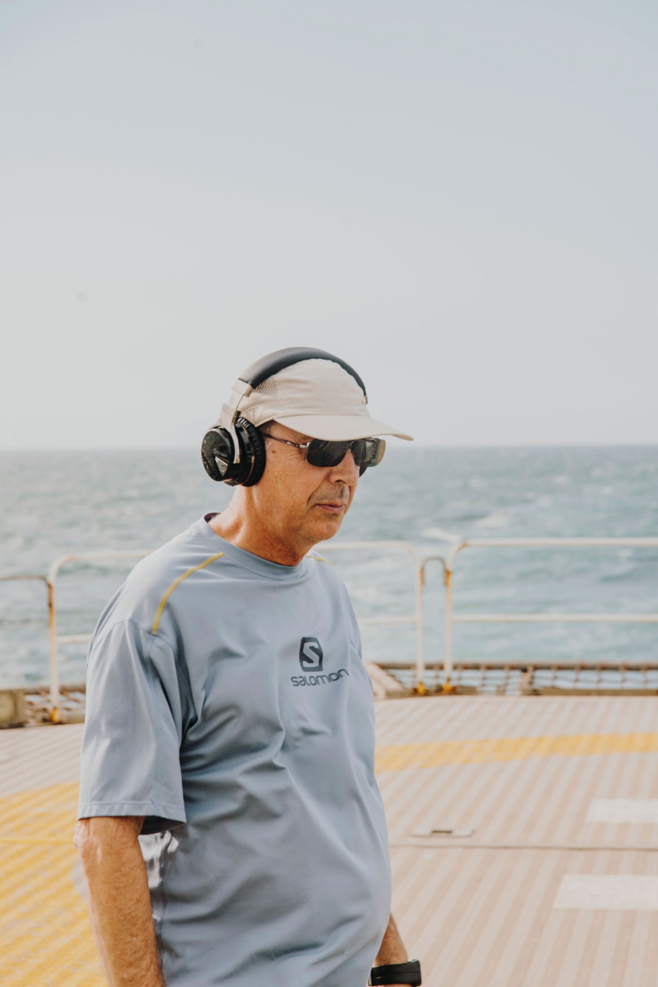 Captain Carlos García Rodríguez wearing headphones, sunglasses and a visor, exercising on the deck of the Esperanza del Mar with the ocean visible in the background.