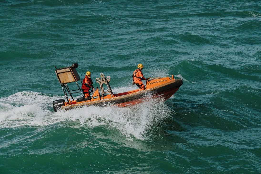 Orange rescue speedboat with crew members in safety gear approaching through Atlantic waves near Esperanza del Mar.