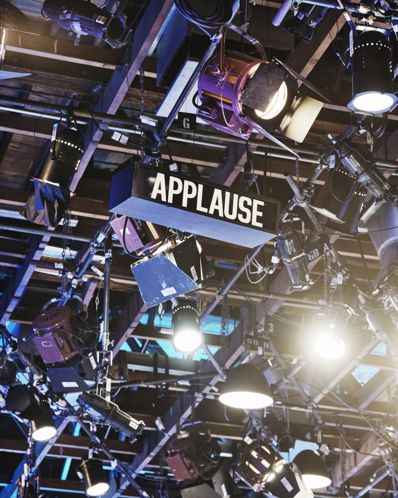 Overhead view of studio lighting rig with 'APPLAUSE' sign visible among professional equipment