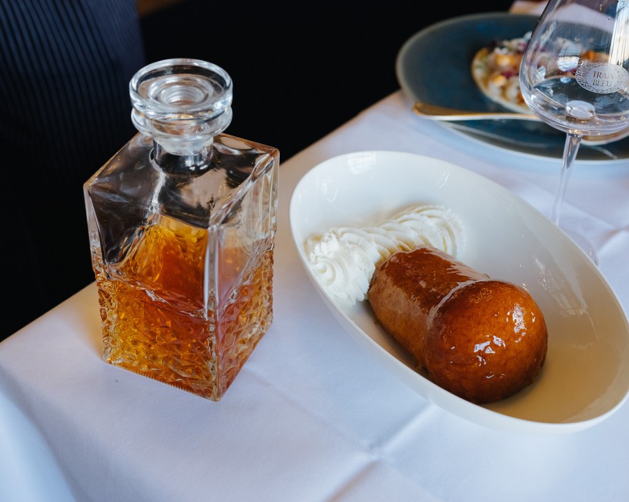 Baba au Rhum dessert with rum bottle and whipped cream at Le Train Bleu restaurant.