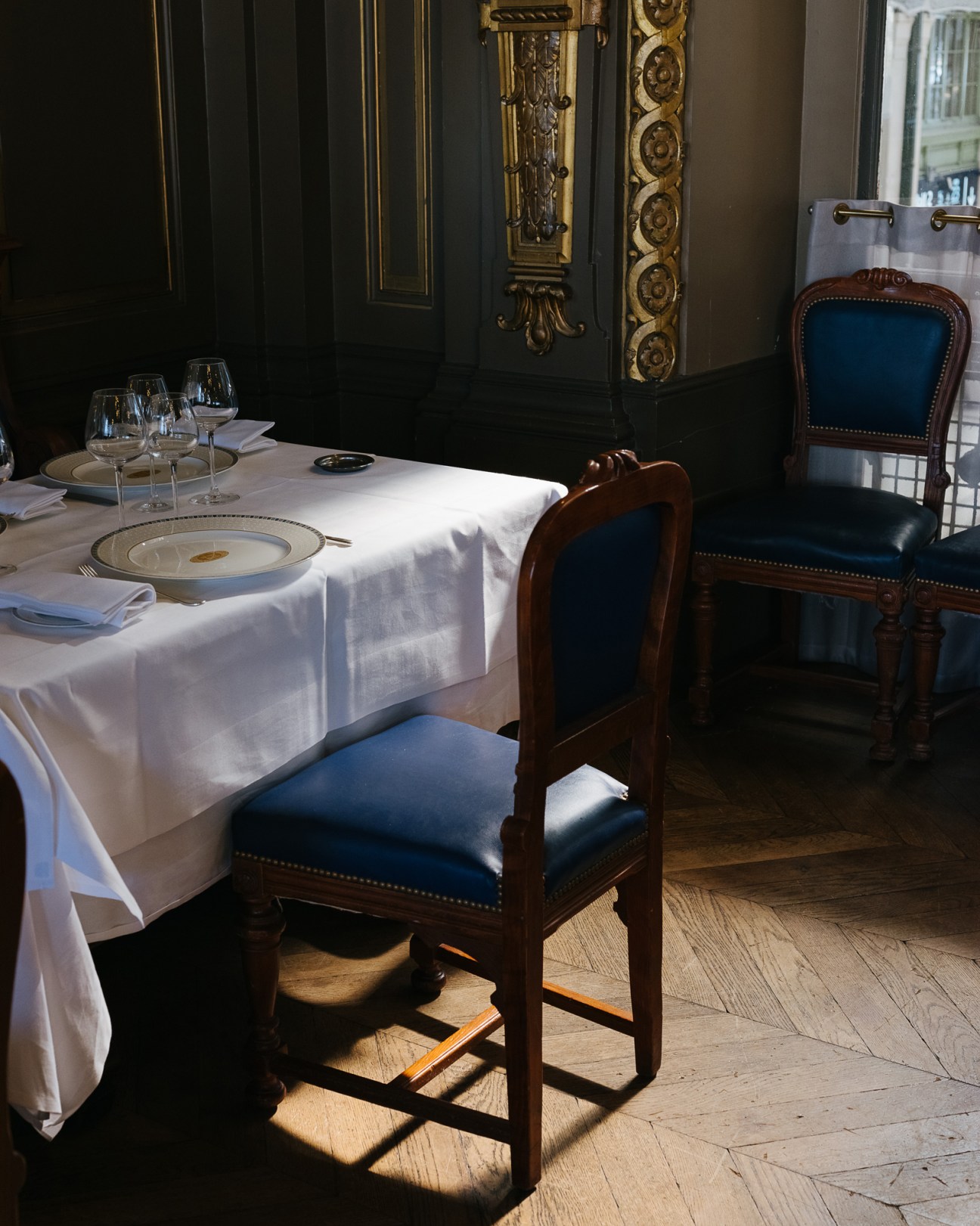 Elegant dining table with white linens, place settings, and blue leather chairs at Le Train Bleu restaurant.