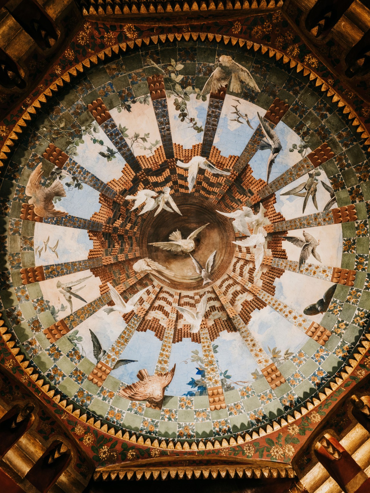 Ornate ceiling dome with hand-painted tiles featuring birds, floral motifs, and geometric patterns in earth tones and blue.