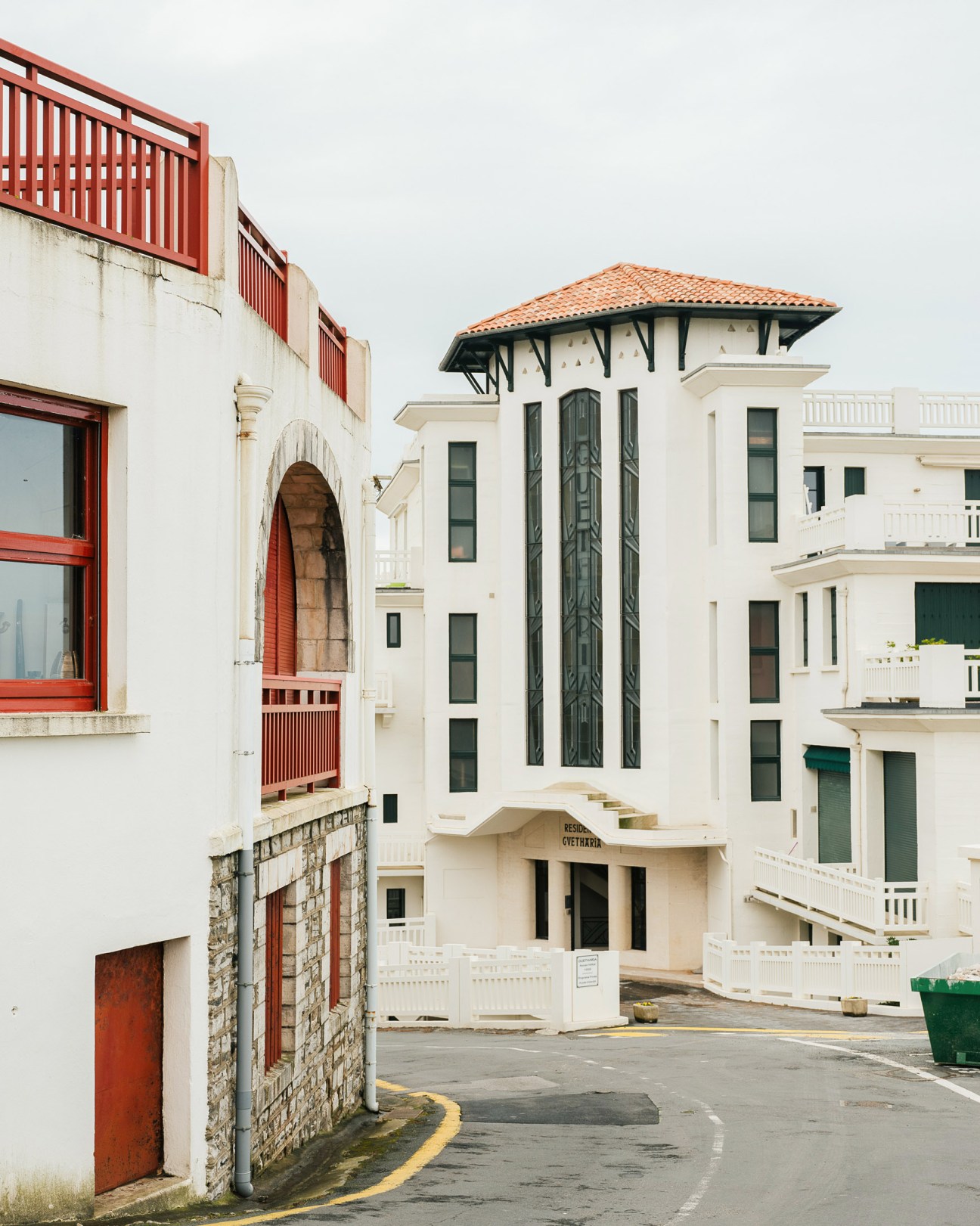 White buildings with terracotta tile roofs and red doors in Guéthary's Néobasque architectural style.