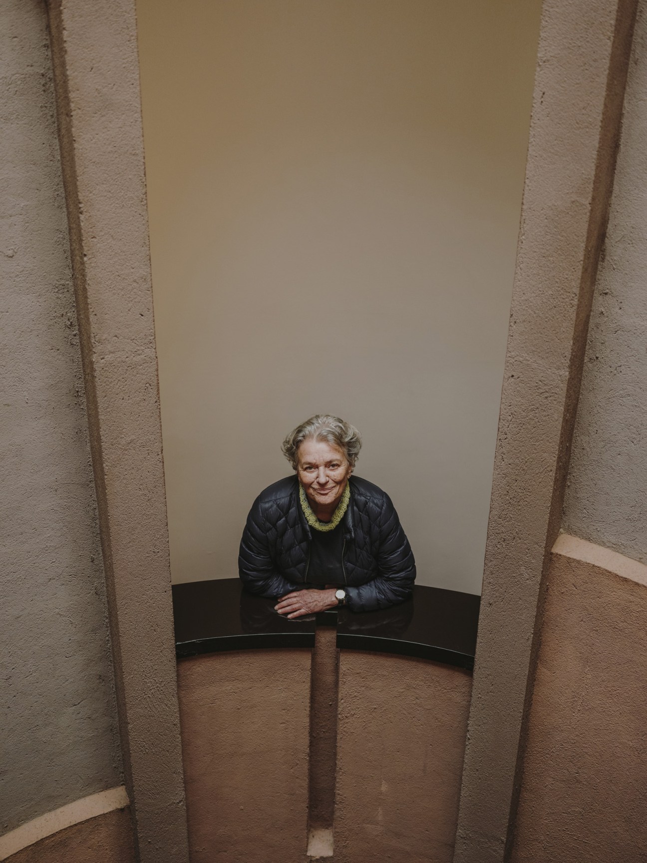 Serena Vergano, publications manager, sits at a curved desk in a concrete alcove with whitewashed walls.