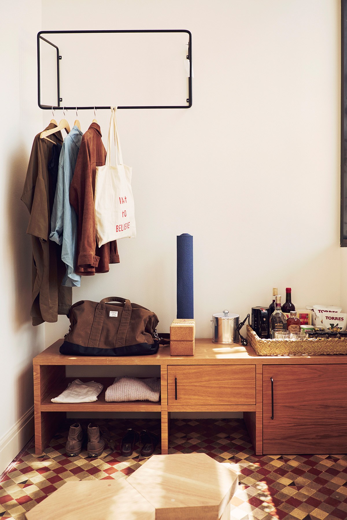 Hotel room detail with wooden storage unit, wall-mounted clothing rack, and minimalist decor at Casa Bonay.