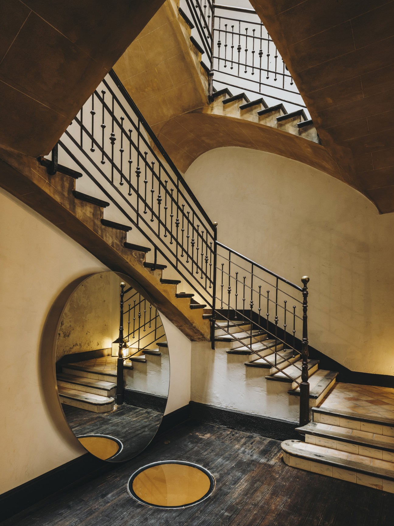 Grand spiral staircase with black metal railings and ornate balusters in renovated Palma palace hotel