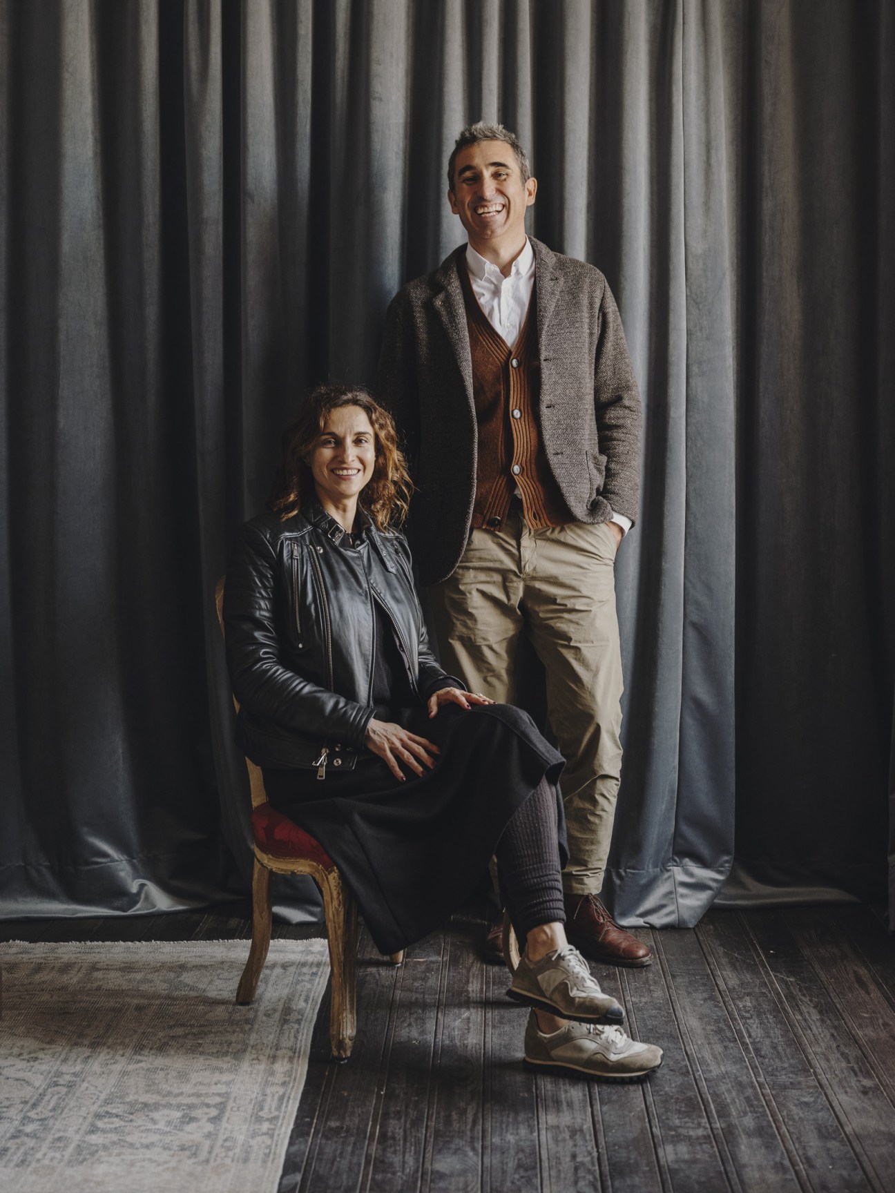 Architects Paloma Hernaiz and Jaime Oliver standing together against a grey curtain backdrop.