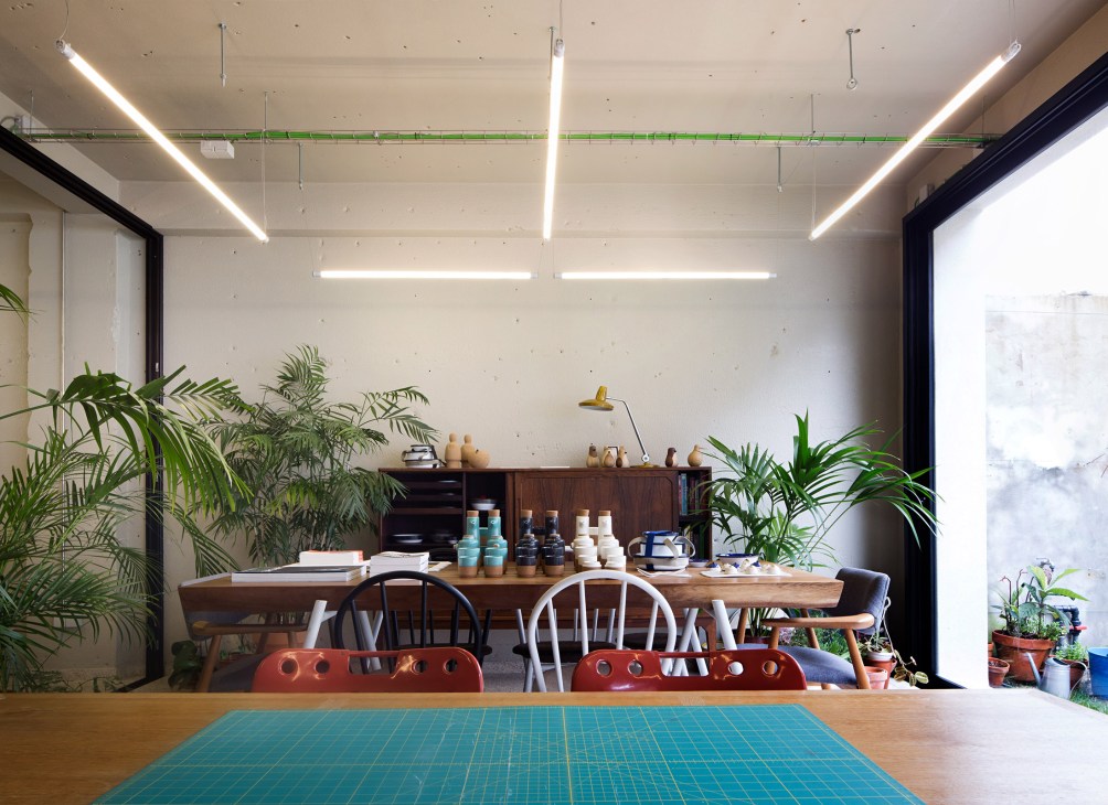 Interior of EarlyMade shop showing a wooden desk with plants, workspace, and natural lighting from the window.
