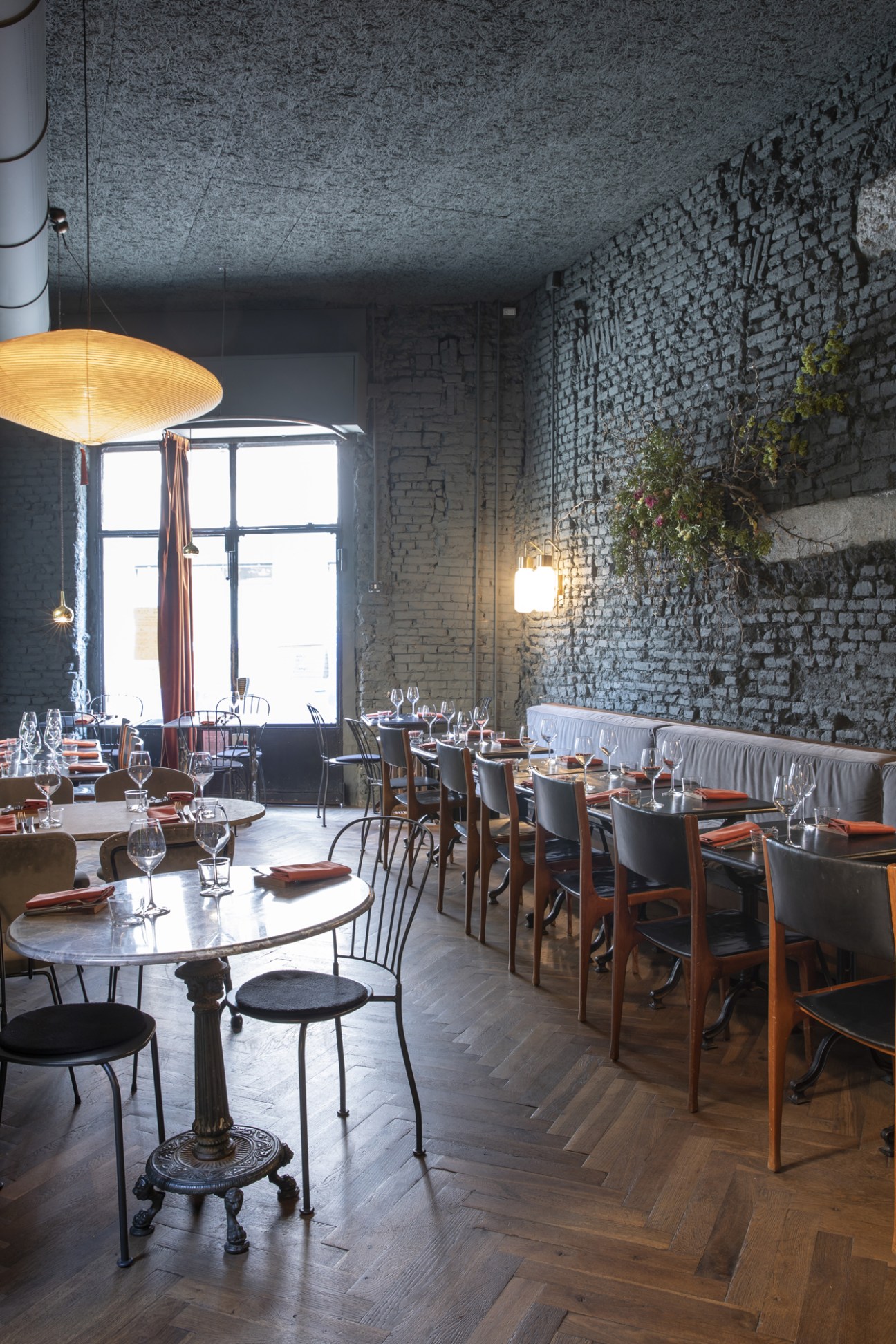 Sixième bistro interior with exposed brick walls, pendant lighting, and wooden dining chairs arranged at tables.