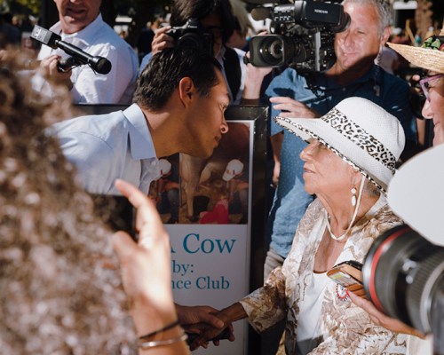 Julián Castro waving to supporters at Iowa State Fair surrounded by media and crowd.
