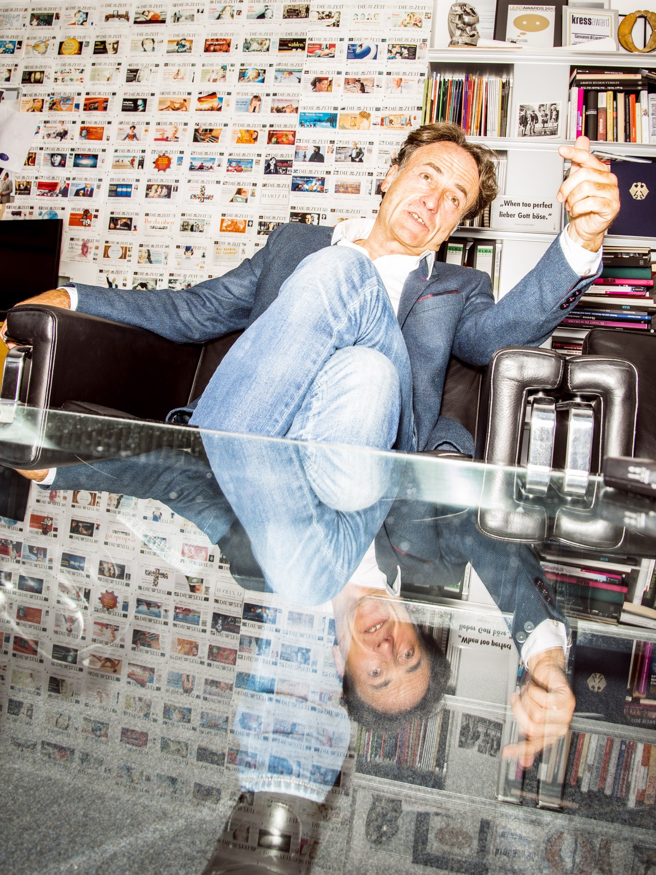 Giovanni di Lorenzo, editor in chief of Die Zeit, relaxes in his office surrounded by newspaper covers.