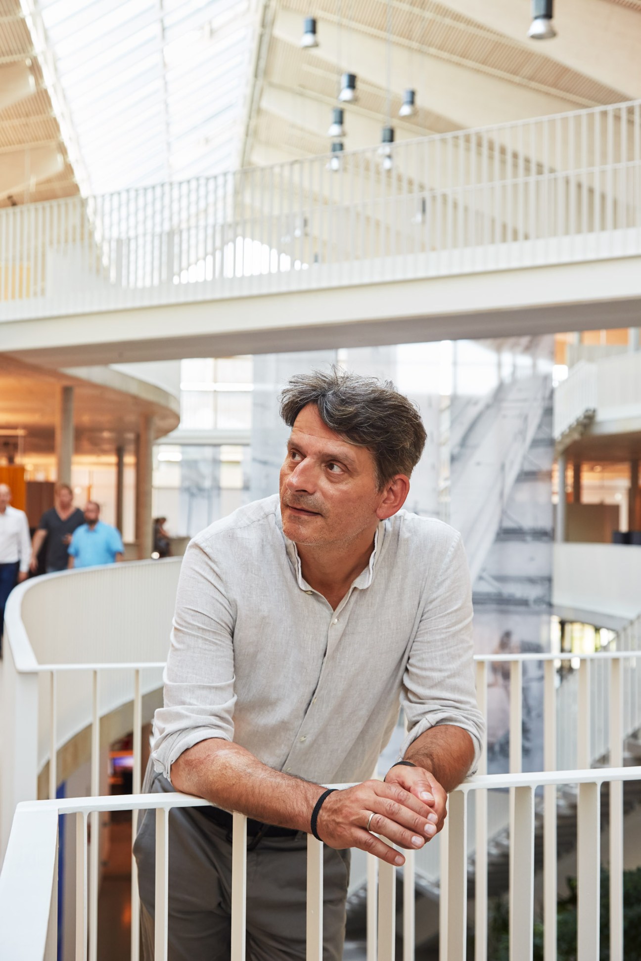 Architect Martin Haas standing in the bright multi-level Alnatura Campus interior with natural light and white railings visible