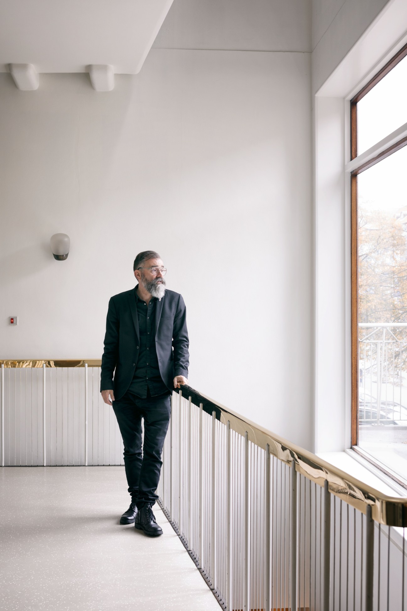 Aarhus city architect Stephen Willacy standing in a minimalist hallway with white walls and metal railings.