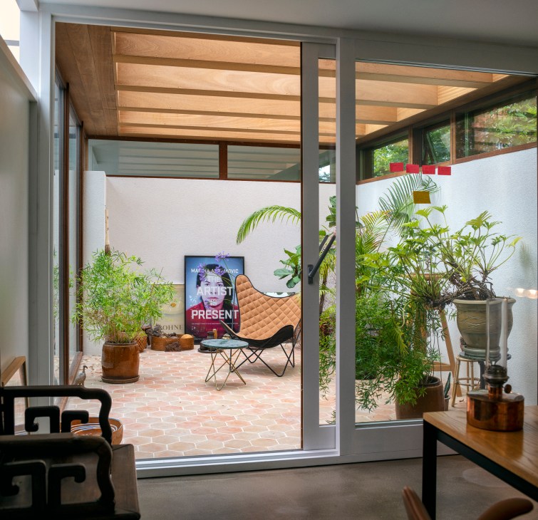 Living room interior with abundant plants, wooden furniture and sliding glass doors to garden