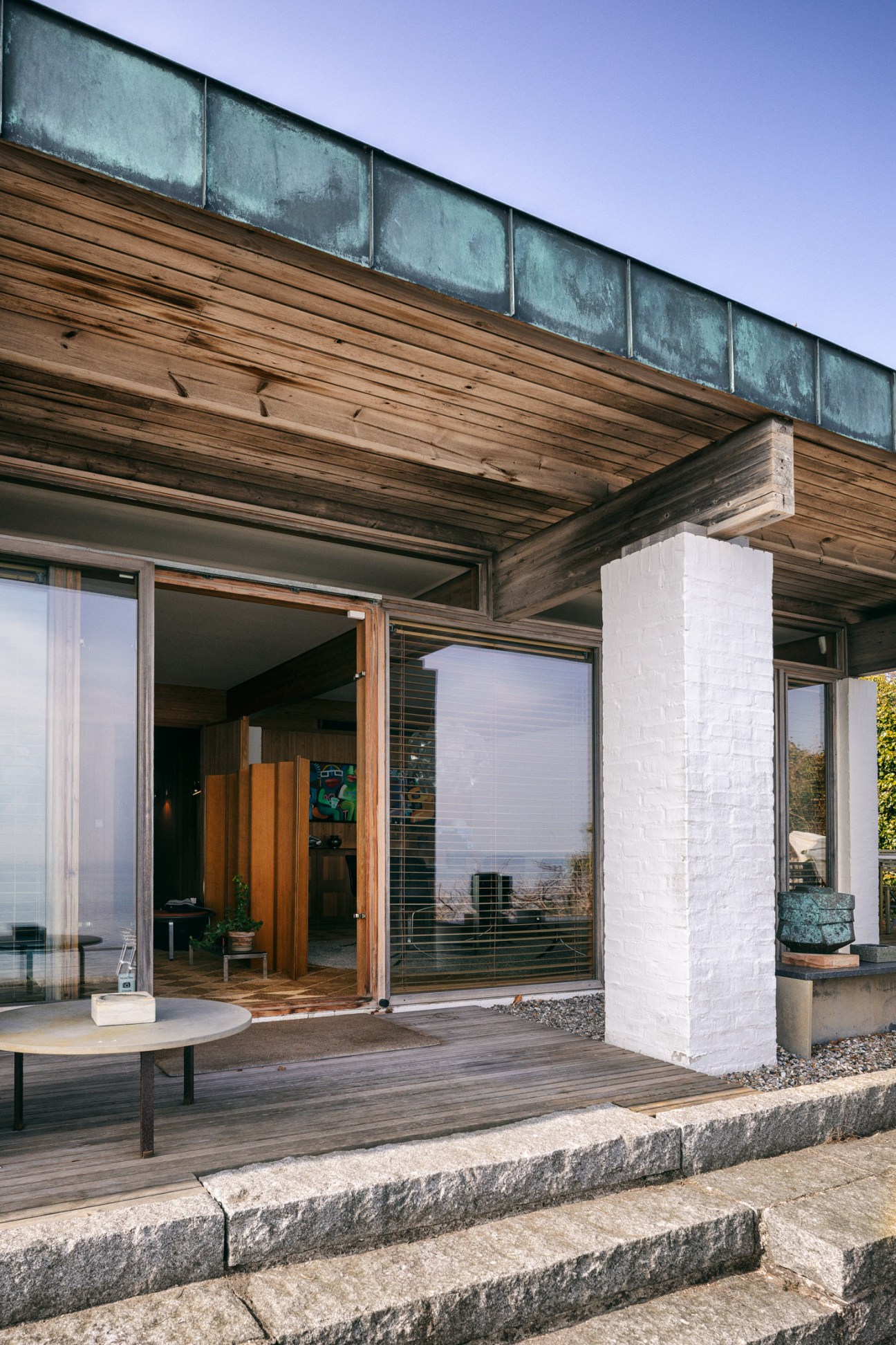 Wooden deck overlooking the strait of Øresund with modernist furniture arranged for outdoor relaxation
