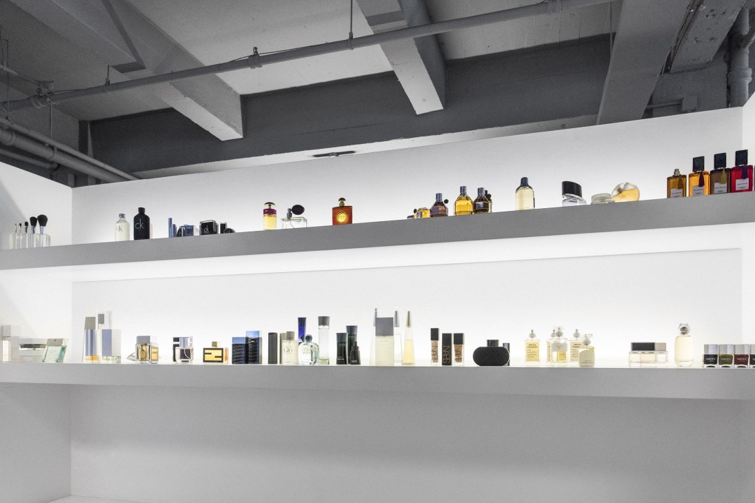 Array of designer perfume and cologne bottles displayed on minimalist shelves.