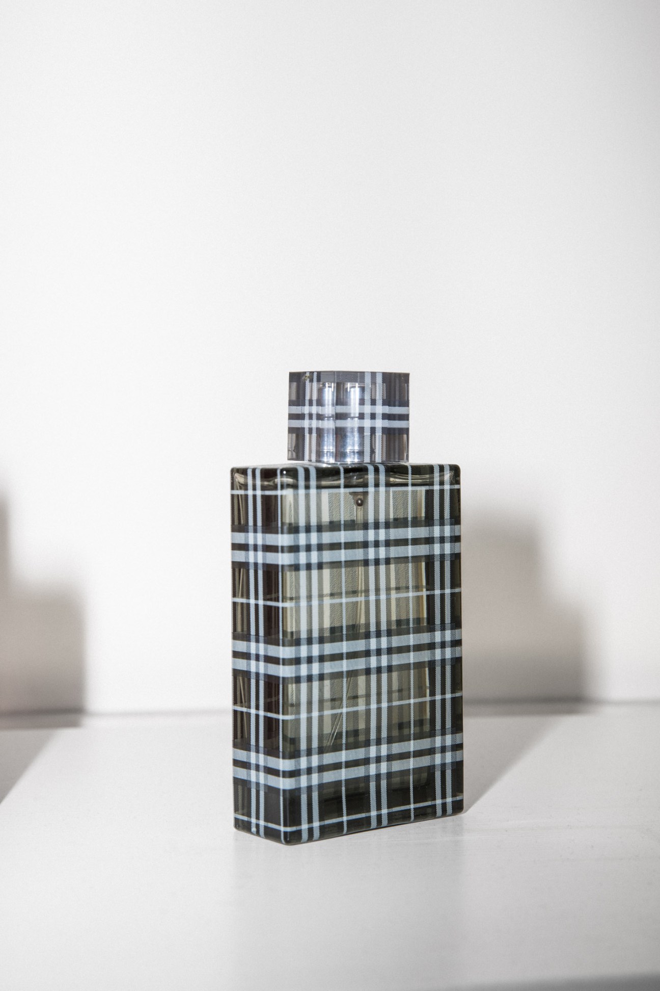 Burberry Brit men's fragrance bottle with black and white tartan pattern and silver cap.
